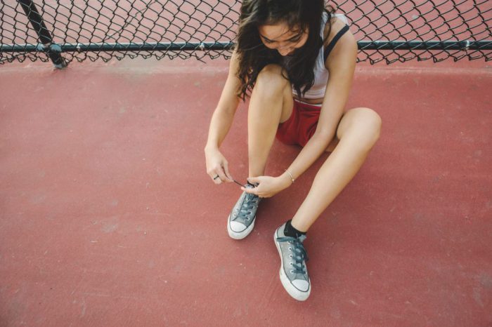 Young woman tying shoelace on basketball court Young woman tying shoelace on basketball court